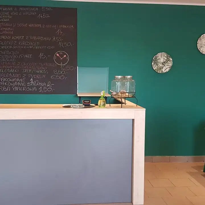 Szara lada przed zieloną ścianą z tablicą